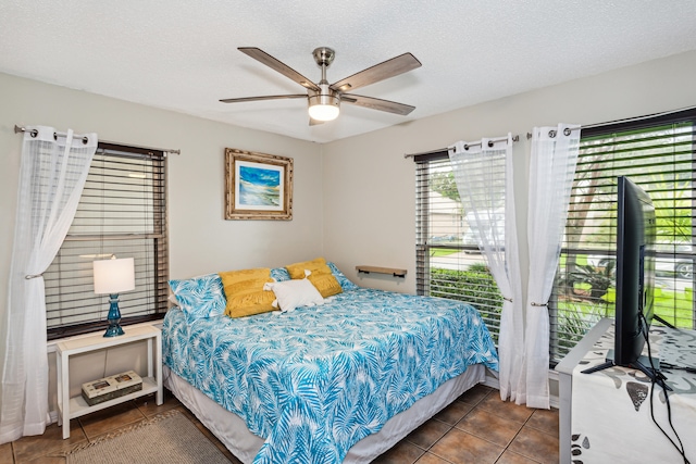 bedroom with dark tile patterned flooring, multiple windows, a textured ceiling, and ceiling fan