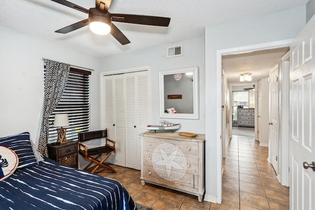 bedroom featuring a closet, a textured ceiling, light tile patterned flooring, and ceiling fan