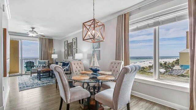 dining area with a water view, a wealth of natural light, crown molding, and wood finished floors
