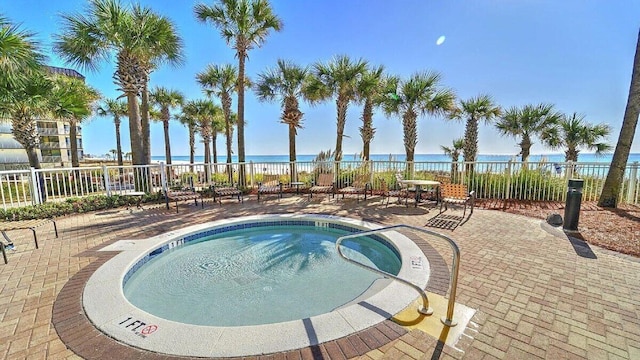 view of swimming pool featuring a water view, a hot tub, and a patio