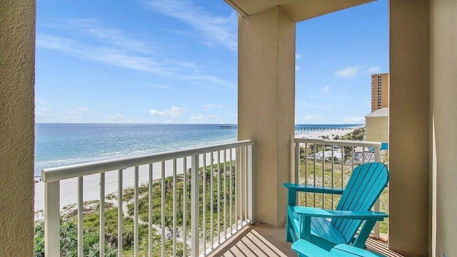 balcony featuring a view of the beach and a water view