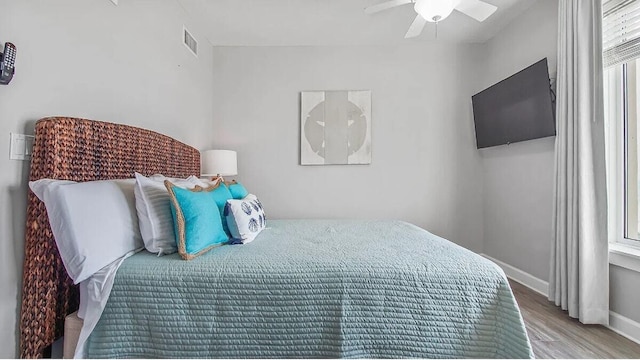 bedroom featuring ceiling fan, baseboards, visible vents, and wood finished floors
