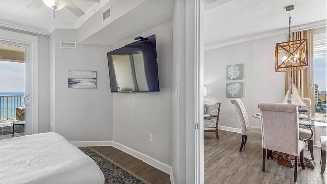 bedroom with baseboards, ornamental molding, visible vents, and wood finished floors
