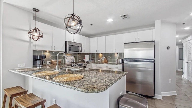 kitchen featuring kitchen peninsula, white cabinetry, stainless steel appliances, and pendant lighting