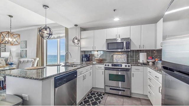 kitchen featuring white cabinetry, dark stone counters, sink, stainless steel appliances, and a water view