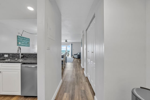 corridor with light wood-type flooring and sink