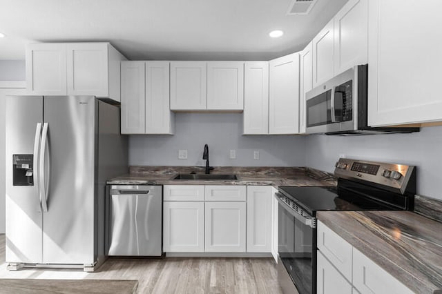 kitchen with stainless steel appliances, white cabinets, and sink