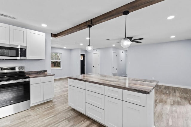 kitchen featuring white cabinets, stainless steel appliances, pendant lighting, and wood counters