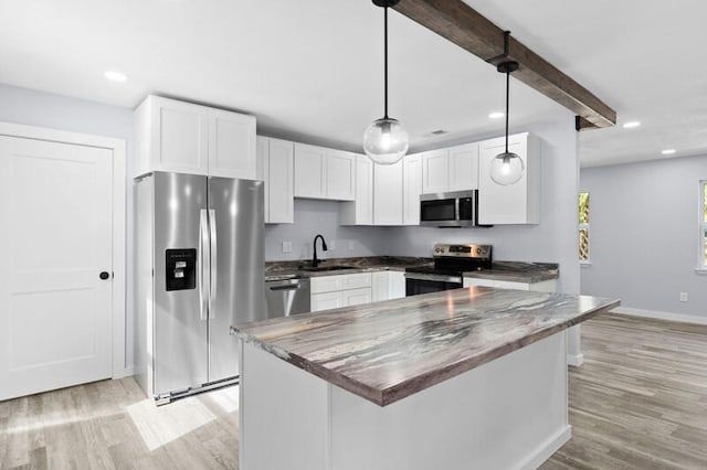 kitchen with light hardwood / wood-style floors, white cabinets, sink, appliances with stainless steel finishes, and decorative light fixtures