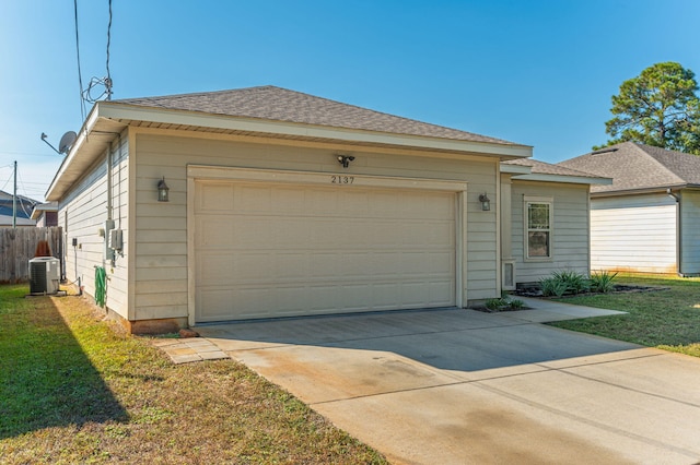 view of front of property featuring a front yard, central AC, and a garage