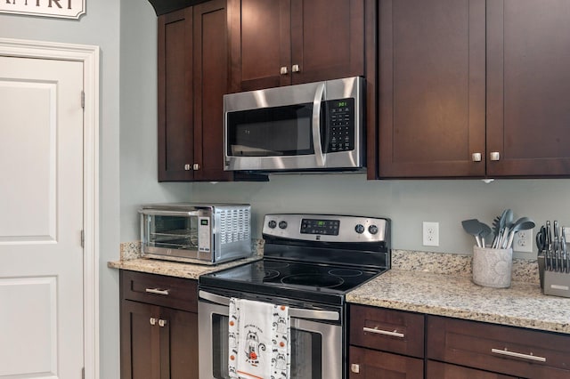 2137 Janet St, Navarre, FL 32566 - kitchen with appliances with stainless steel finishes, dark brown cabinets, and light stone countertops