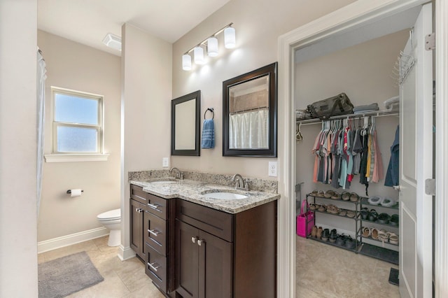 2137 Janet St, Navarre, FL 32566 - bathroom featuring double vanity, baseboards, toilet, a spacious closet, and tile patterned floors