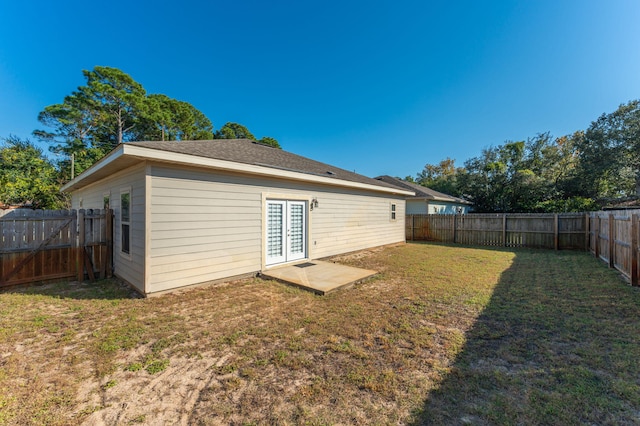 back of house with french doors and a lawn