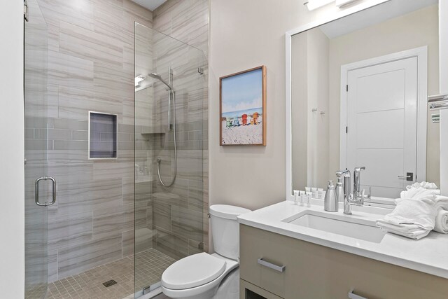 bathroom with vanity, toilet, and a shower with door