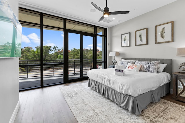 bedroom with ceiling fan, a wall of windows, hardwood / wood-style floors, and access to exterior