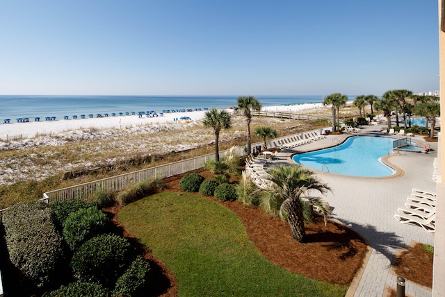 view of swimming pool featuring a water view, a view of the beach, and a patio