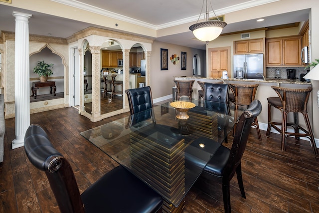 dining room with dark wood-type flooring, crown molding, and decorative columns