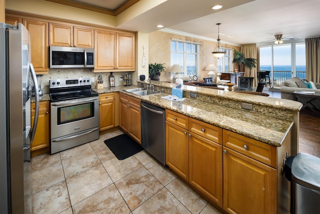 kitchen featuring kitchen peninsula, appliances with stainless steel finishes, ornamental molding, sink, and a water view