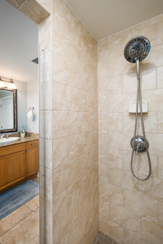 bathroom featuring vanity, tile patterned flooring, and tiled shower