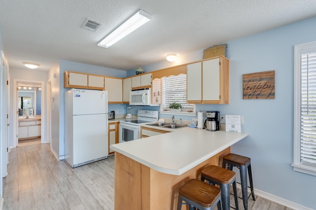 kitchen featuring light hardwood / wood-style flooring, kitchen peninsula, a textured ceiling, and white appliances