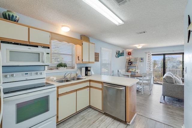 kitchen featuring light hardwood / wood-style flooring, kitchen peninsula, sink, and white appliances