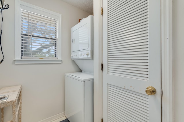 laundry area featuring a textured ceiling and stacked washing maching and dryer