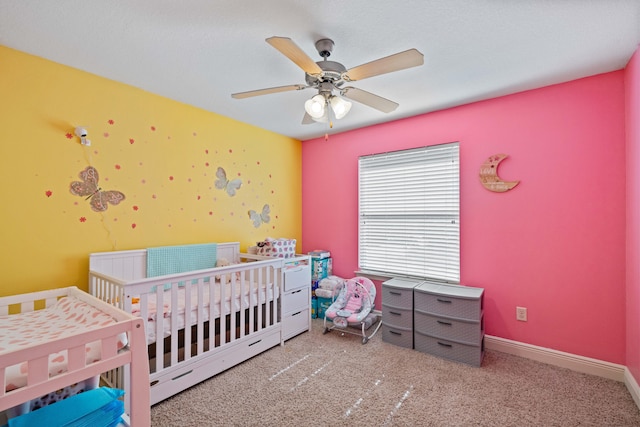 carpeted bedroom featuring ceiling fan and a crib