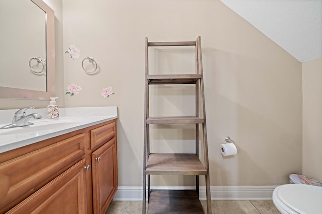 bathroom featuring toilet, vanity, vaulted ceiling, and tile patterned flooring