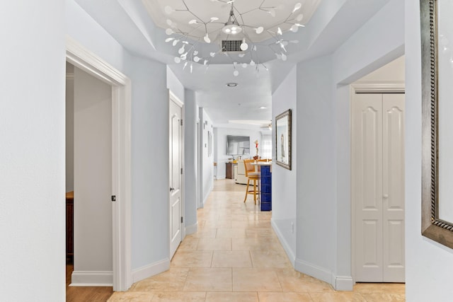 hall with a notable chandelier and light tile patterned floors