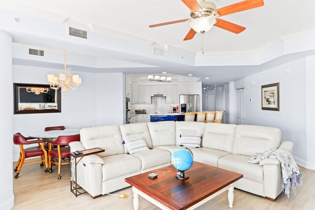 living room with ornamental molding, light hardwood / wood-style flooring, and ceiling fan with notable chandelier