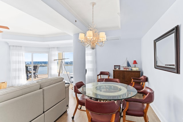 dining area featuring a water view, light hardwood / wood-style floors, ornamental molding, and an inviting chandelier