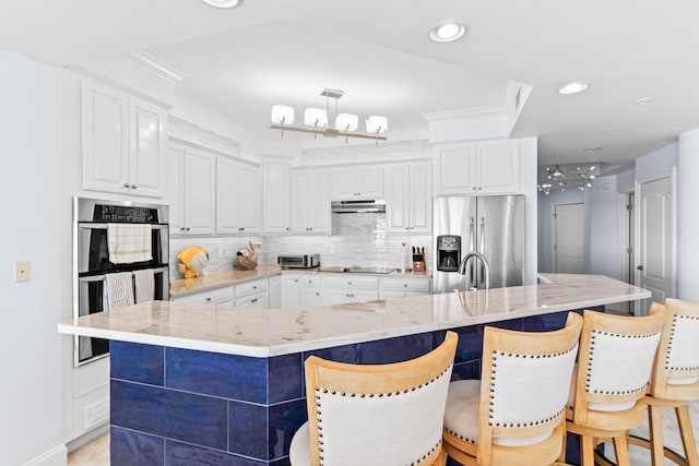 kitchen featuring a large island, appliances with stainless steel finishes, a kitchen breakfast bar, and white cabinets