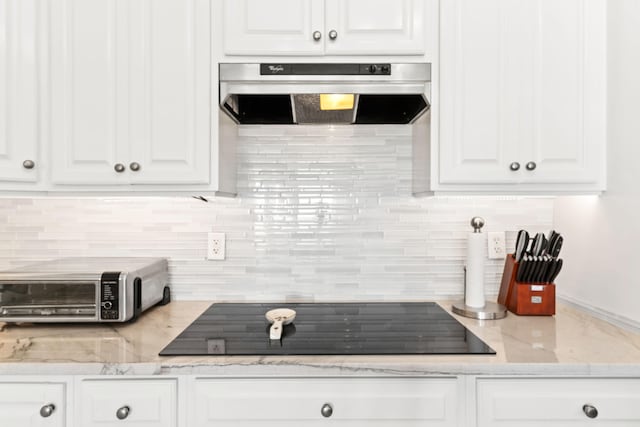 kitchen with exhaust hood, white cabinetry, black electric stovetop, and tasteful backsplash