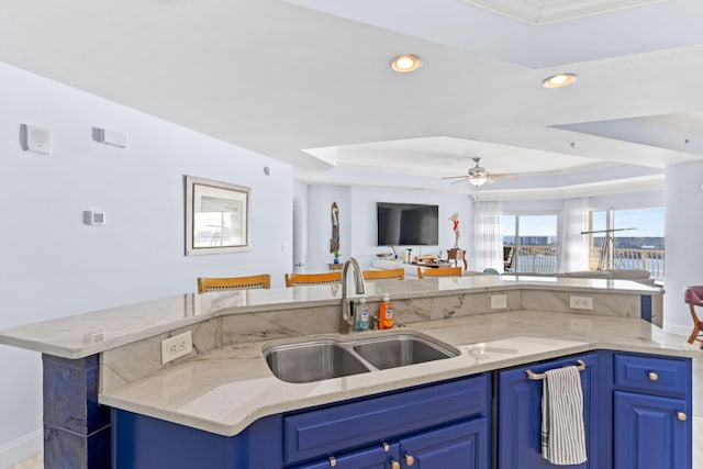 kitchen with sink, a tray ceiling, and blue cabinets