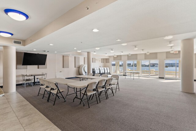 dining area featuring a water view, a textured ceiling, and light tile patterned floors