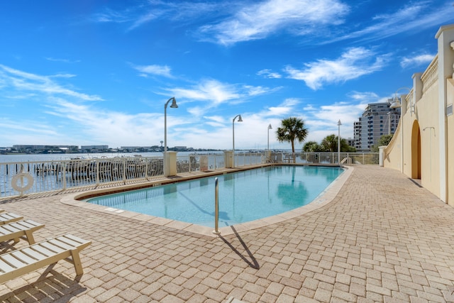 view of pool with a water view and a patio