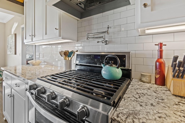 kitchen with light stone countertops, white cabinets, tasteful backsplash, and stainless steel gas stove