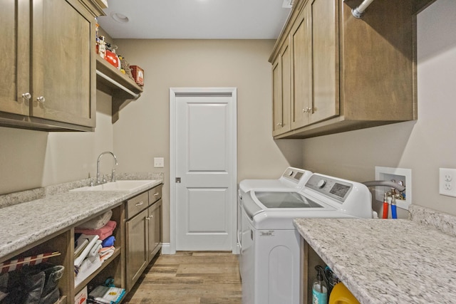 clothes washing area featuring sink, independent washer and dryer, cabinets, and light hardwood / wood-style flooring