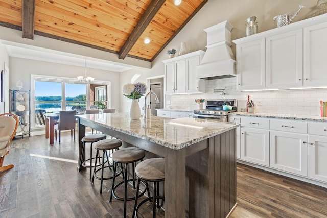 kitchen featuring stainless steel range, white cabinetry, custom range hood, and wooden ceiling