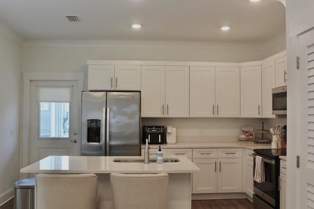 kitchen featuring appliances with stainless steel finishes, sink, dark hardwood / wood-style flooring, white cabinetry, and a kitchen island with sink