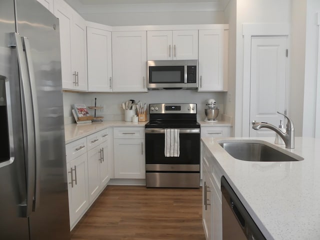 kitchen with appliances with stainless steel finishes, white cabinetry, light stone countertops, and sink