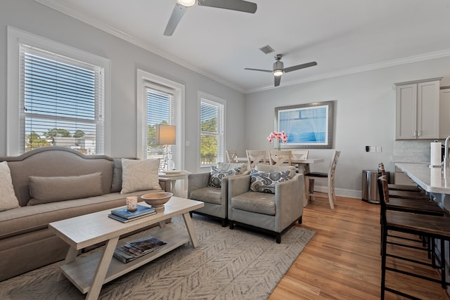 living room with crown molding, light wood-type flooring, and ceiling fan