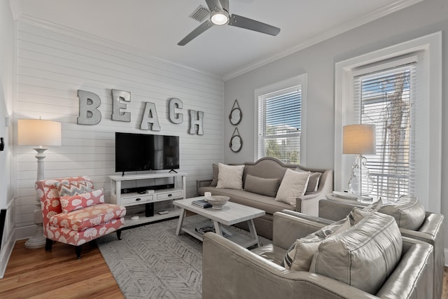 living room with light hardwood / wood-style floors, crown molding, and ceiling fan