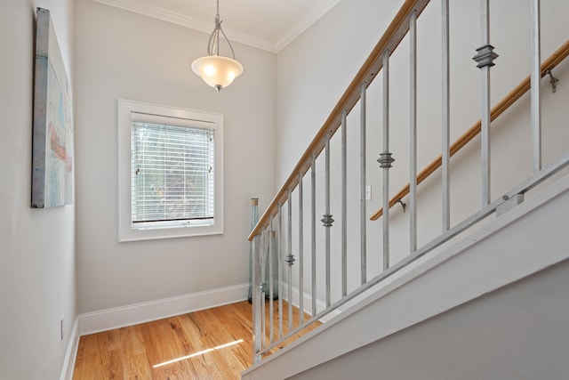 staircase with ornamental molding and hardwood / wood-style floors