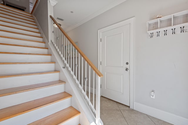 stairway with tile patterned floors and ornamental molding