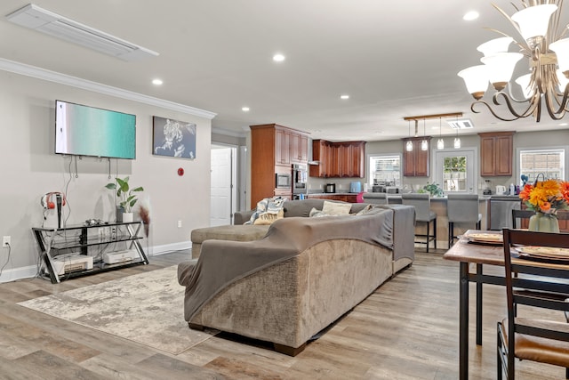 living room featuring light hardwood / wood-style floors, ornamental molding, and a chandelier