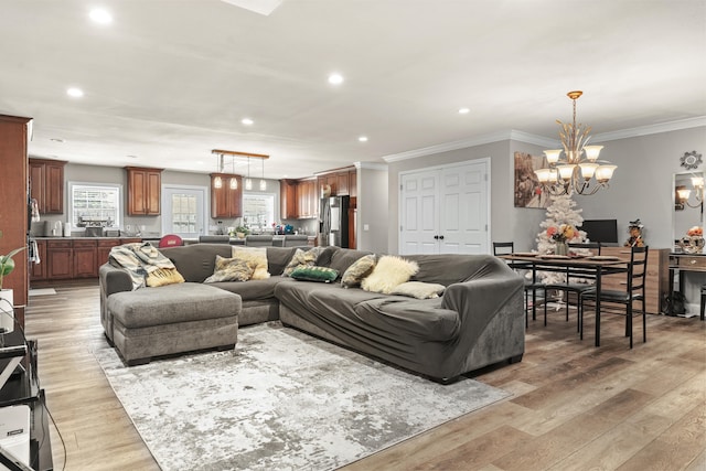 living room with a chandelier, light wood-type flooring, and crown molding