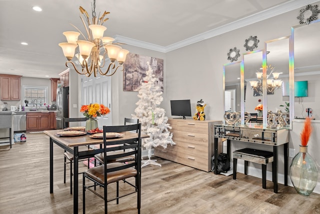 dining space with crown molding, light hardwood / wood-style flooring, a chandelier, and sink