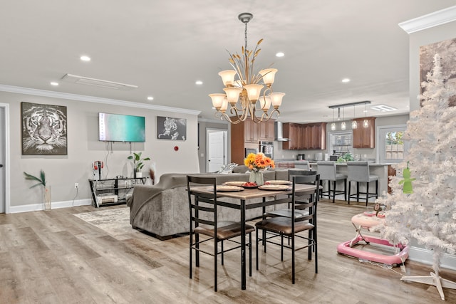 dining room featuring light hardwood / wood-style floors, ornamental molding, and a notable chandelier