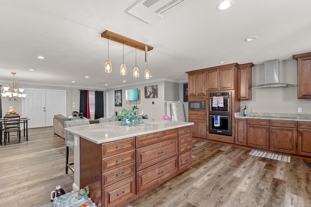 kitchen featuring pendant lighting, stainless steel double oven, wall chimney range hood, and ornamental molding